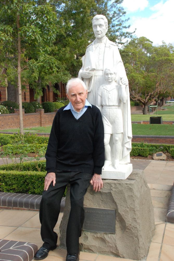 Brother McGlade in front of the Blessed Edmund Rice Statue at the College